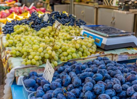 Plums, black and white grapes on marketplace